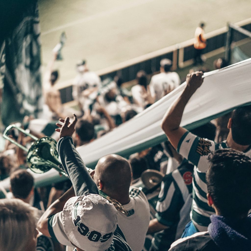 Supporters en liesse dans tribune, bras levés, grande banderole blanche : les médias vous rapprochent de vos prospects